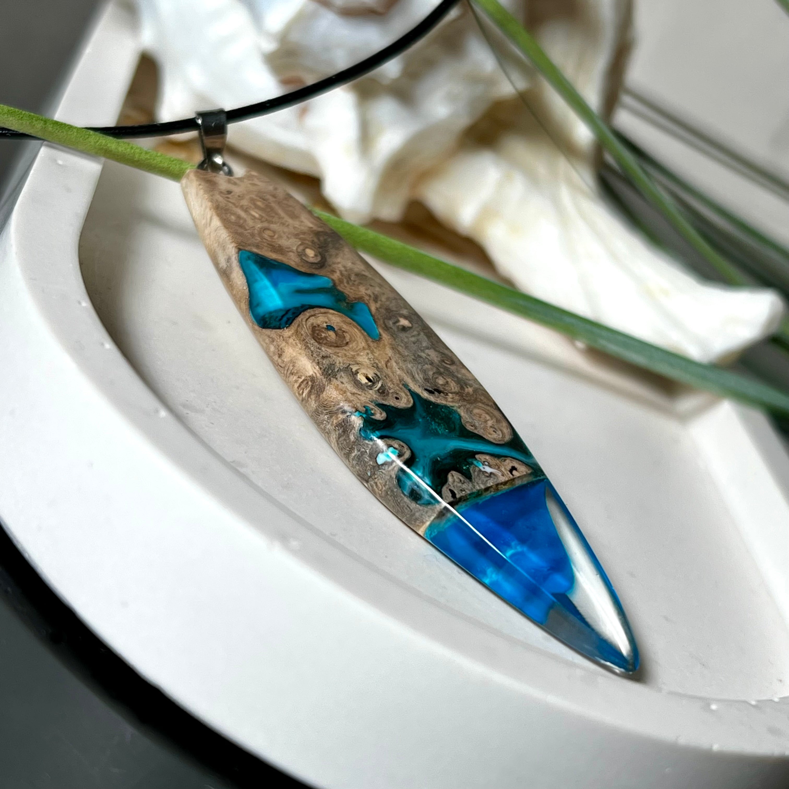 Handgefertigter Surfbrett-Anhänger aus Maserholz und transparentem Harz mit Farbverlauf in Blau und Weiß. Die natürliche Maserung des Holzes trifft auf ozeanartige Harzstrukturen. Größe ca. 6,7 x 2 cm, mit Edelstahlöse und Lederband inkl. Karabinerverschluss (45 cm + 5 cm Verlängerung). Jedes Stück ist ein Unikat – maritim, modern und mit viel Liebe gefertigt.