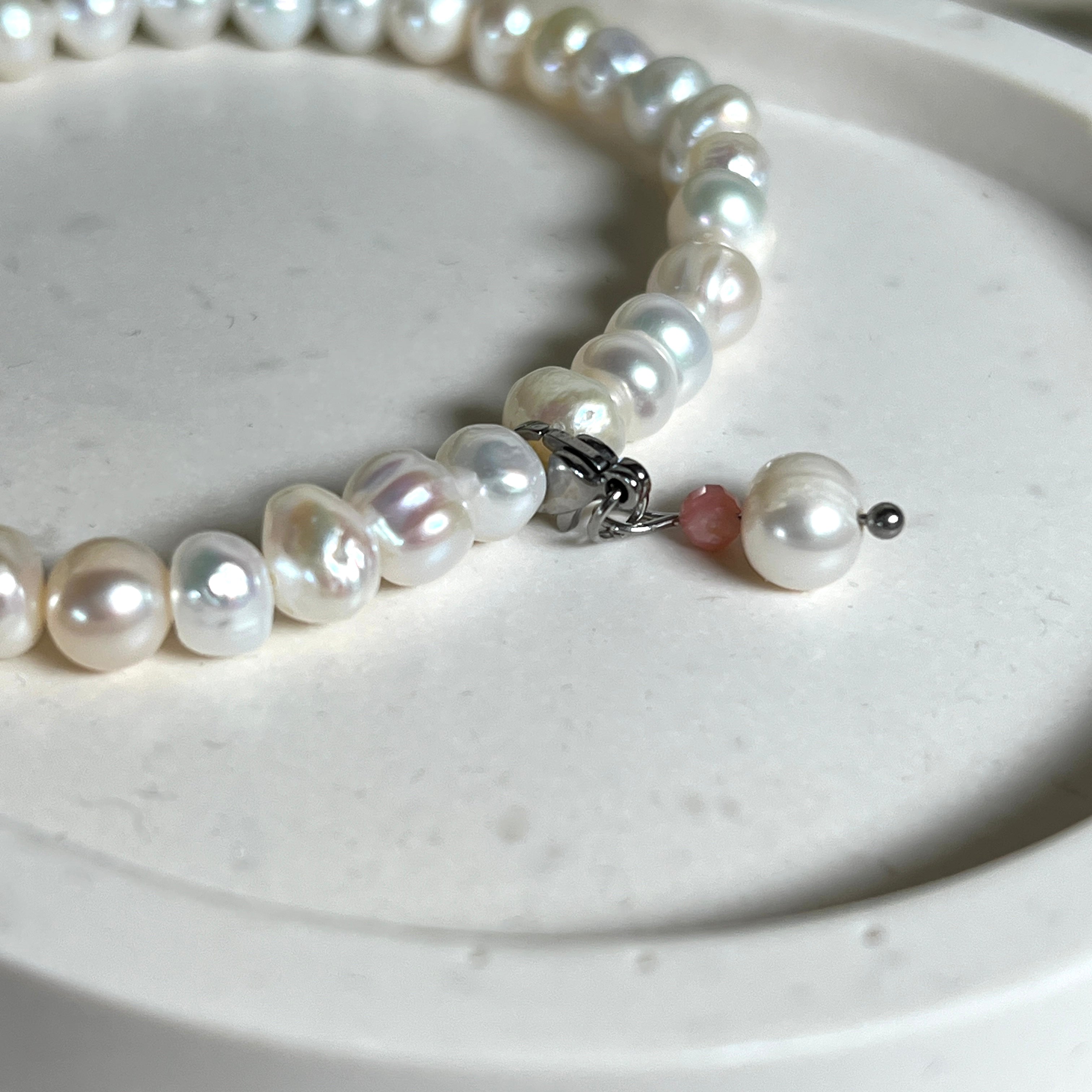 Handgefertigtes Armband „Ocean Bloom“ mit echten, schimmernden Süßwasserperlen (Ø ca. 6–7 mm) auf elastischem Band. Jede Perle ist ein Unikat mit natürlicher Form und sanftem Glanz. Highlight: Charmanhänger mit einer Süßwasserperle und einer facettierten Andenopal-Perle, befestigt an einem robusten Edelstahl-Karabiner. Ein Schmuckstück voller Eleganz, Symbolkraft und maritimer Schönheit.
