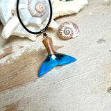 Handgefertigter Walflossen-Anhänger aus Olivenholz und Epoxidharz in Blau-Grün-Weiß, polierte Oberfläche, Edelstahl-Öse. Schwarze Lederkette 45 cm mit Edelstahl-Karabinerverschluss und 5 cm Edelstahl-Verlängerung. Anhängergröße ca. 2,5 × 3,2 cm, maritime Produktfotografie.