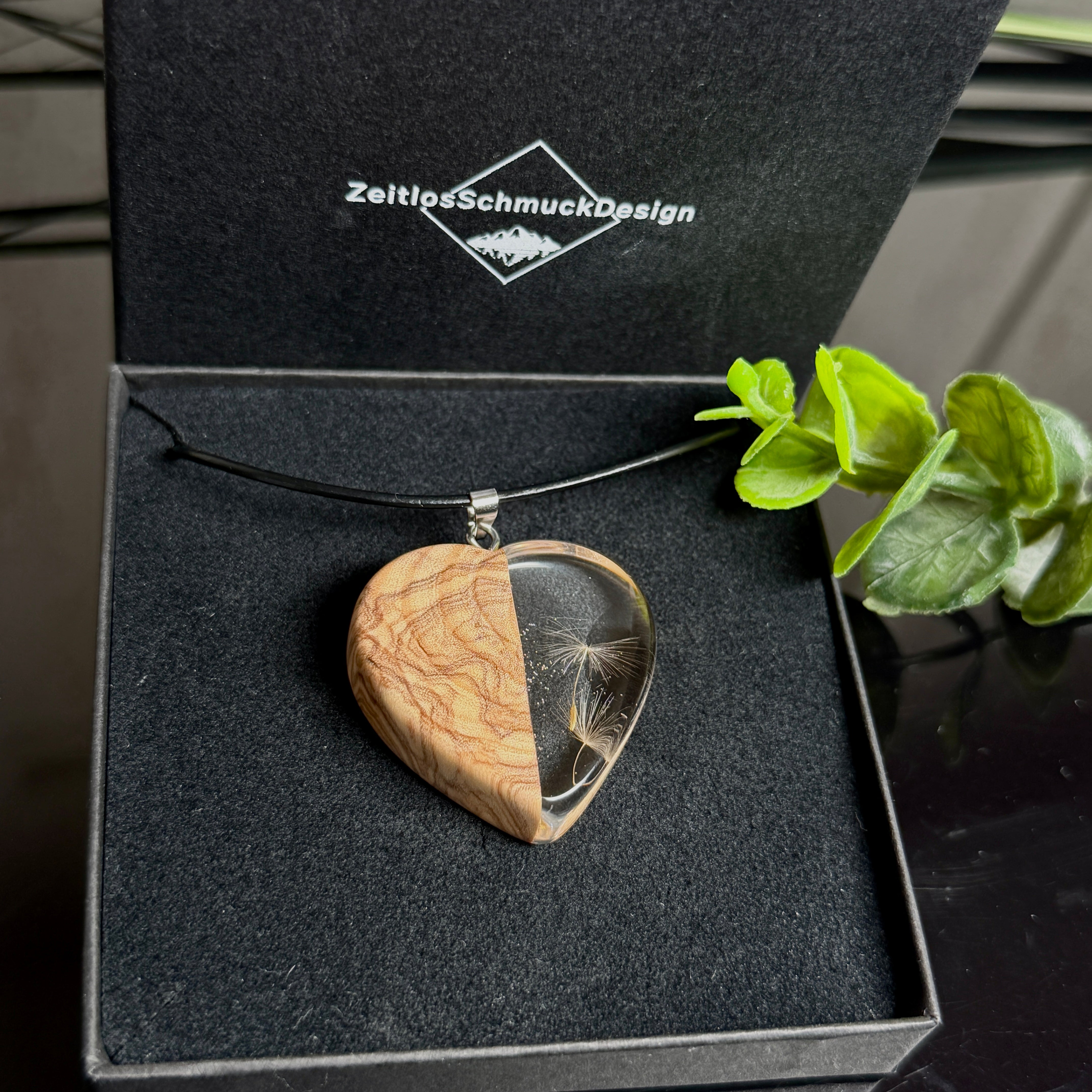 Pusteblumen Herzanhänger aus Olivenholz und glasklarem Epoxidharz, echte Löwenzahnsamen im Harz schwebend, schwarze Lederkette, handgefertigter Naturschmuck in Schmuckbox. 