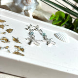 Edle „Ocean Star“ Ohrringe aus 925 Sterling Silber mit Seestern-Anhängern (18 × 17 mm), verziert mit einer aquablauen Apatitperle und funkelndem Zirkonia. Länge getragen: 45 mm. Maritime Schmuckstücke, die das Funkeln des Meeres einfangen – elegant, hochwertig und ein ideales Geschenk für Meeresliebhaber und Sommerträume.