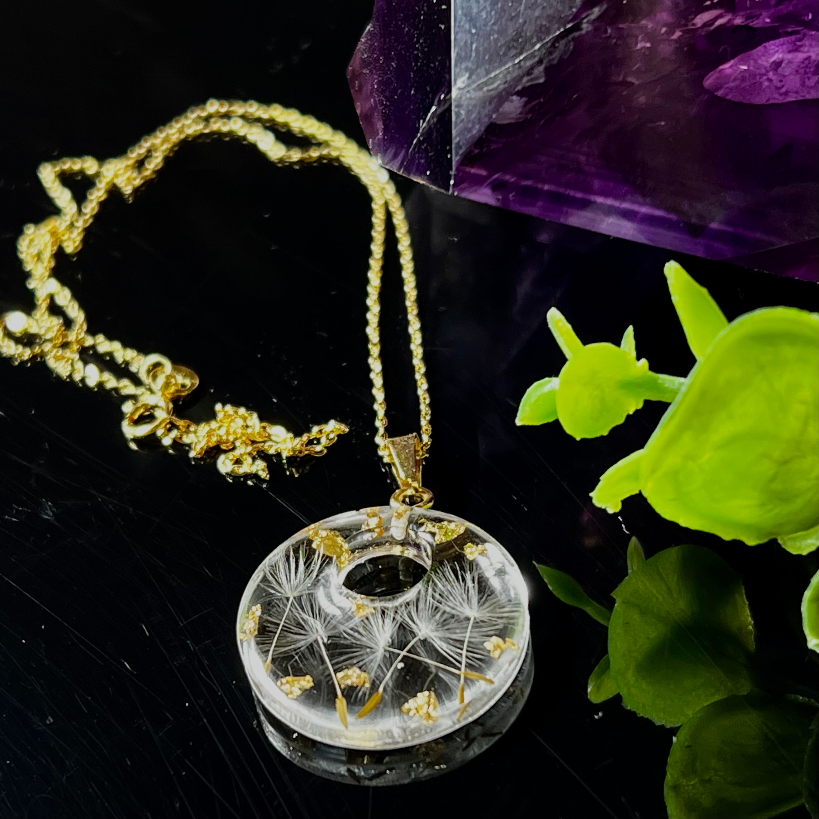 Runder Harzanhänger mit echten Pusteblumensamen und zarten Blattgold-Akzenten auf einer vergoldeten 925 Silberkette, 45 cm lang. Der Anhänger hat einen Durchmesser von ca. 2,6 cm und wird von einer goldfarbenen Edelstahlöse gehalten. Das Design symbolisiert Leichtigkeit, Hoffnung und Naturverbundenheit – perfekt als Geschenk oder für Naturliebhaberinnen. Liebevoll von Hand gefertigt und ein echtes Unikat.