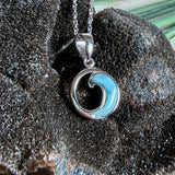 Feine Wellen-Kette aus rhodiniertem 925 Silber. Der runde Anhänger zeigt eine stilisierte Welle mit hellblauem Larimar-Cabochon, eingefasst in poliertem Silber. Größe des Anhängers ca. 23 x 13 mm, an einer 45 cm langen, 1 mm starken, rhodinierten Silberkette. 