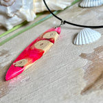 Handgefertigter Surfbrett-Anhänger „Flame Surf“ aus Maserholz und fluoreszierendem Harz in kräftigem Pink. Das Schmuckstück leuchtet bei Schwarzlicht und wird an einer schwarzen Lederkette mit Edelstahl-Karabiner (45 cm + 5 cm Verlängerung) geliefert. Größe ca. 6,7 × 2 cm. Ein Unikat für Surf- und Strandliebhaber, edel verarbeitet und mit Liebe gefertigt.