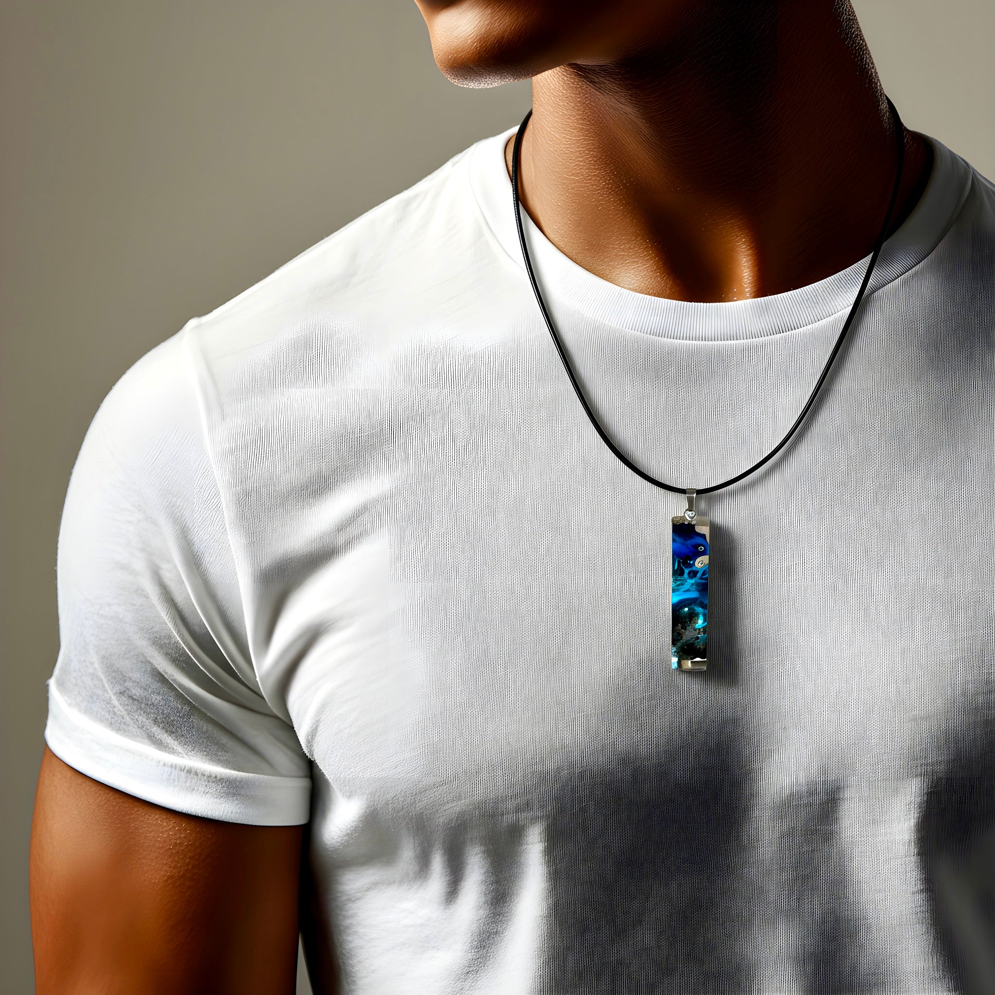 Rechteckiger Stabanhänger aus Maserholz und glasklarem Epoxidharz in tiefen Blau- und Türkistönen mit organischer Lagunen/Riff-Optik. Hochglanzpoliert, ca. 4,6 × 1,2 cm. Der Anhänger hängt an einer schwarzen Lederkette mit Edelstahl-Karabiner und 5-cm-Verlängerung (45 + 5 cm); die Anhängerschlaufe ist ebenfalls aus Edelstahl. Handgefertigtes Unikat, Lieferung in edler Schmuckbox – maritimer Look.