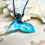 Walflossen-Anhänger „Flossenklang“ – handgefertigtes Unikat aus Maserholz und türkis-blau-grauen und weißem Harz. Die elegant geschwungene Form erinnert an die Flosse eines Wals und symbolisiert Freiheit, Stärke und Naturverbundenheit. Mit verstellbarem braunem Lederband gefertigt, ist jedes Stück ein individuelles Schmuckstück für Meeresliebhaber und Natursuchende. Maritimer Halsschmuck, inspiriert vom Ozean, glatt poliert und mit Liebe zum Detail von Hand gearbeitet.