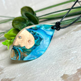 Handgefertigter Anhänger „Ocean Leaf“ aus Maserholz und Epoxidharz in Blau- und Türkistönen. Ein einzigartiges Schmuckstück, das die Schönheit von Natur und Meer einfängt. Mit verstellbarem Lederband (24–43 cm). Jeder Anhänger ist ein Unikat mit einzigartiger Maserung und Farbverlauf.