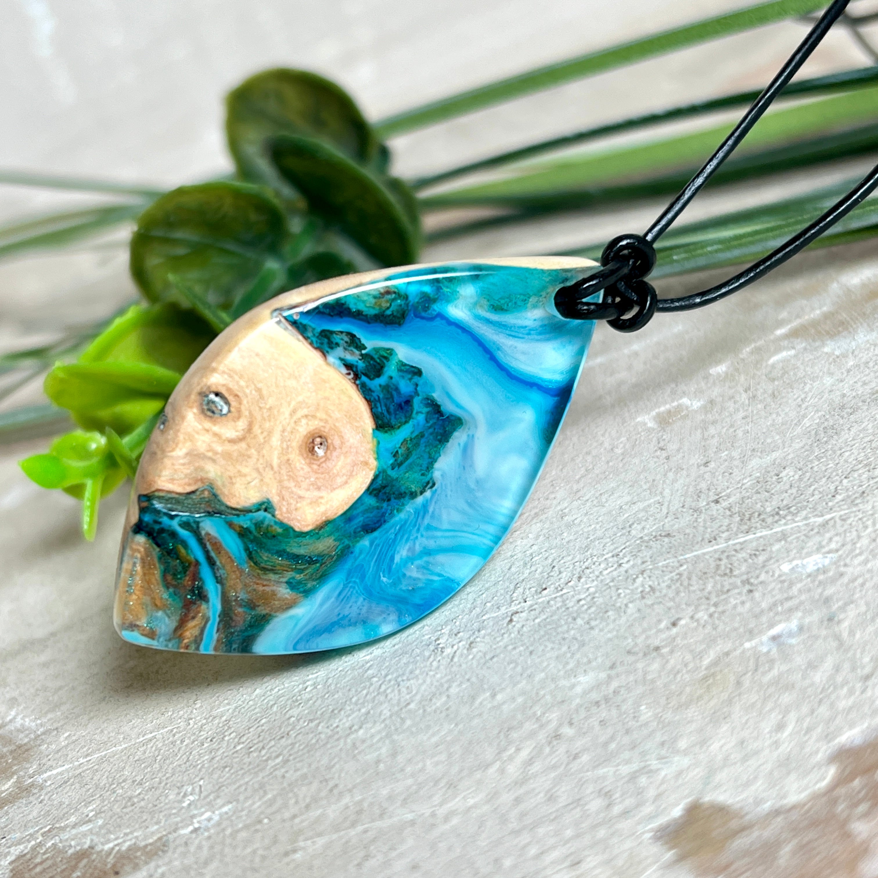 Handgefertigter Anhänger „Ocean Leaf“ aus Maserholz und Epoxidharz in Blau- und Türkistönen. Ein einzigartiges Schmuckstück, das die Schönheit von Natur und Meer einfängt. Mit verstellbarem Lederband (24–43 cm). Jeder Anhänger ist ein Unikat mit einzigartiger Maserung und Farbverlauf.