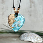 Handgefertigter Herzanhänger aus Maserholz und transparentem Ocean-Harz mit echtem Seestern und Muscheln. Die zarten Aqua-Farben erinnern an Meereswellen. Lederband verstellbar mit Holzperlen. Größe ca. 3,5 × 3,2 cm. Natürliches, maritimes Unikat von ZeitlosSchmuckDesign