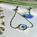 „Handgefertigtes Armband mit echter Vergissmeinnicht-Blume, eingebettet in klares Harz. Verstellbares Edelstahlarmband mit Schiebeverschluss und funkelnden Zirkonia-Endperlen. Symbolträchtiger Schmuck für Frauen – ideal als Geschenk zum Muttertag, Geburtstag oder zur Erinnerung an einen besonderen Menschen.“
