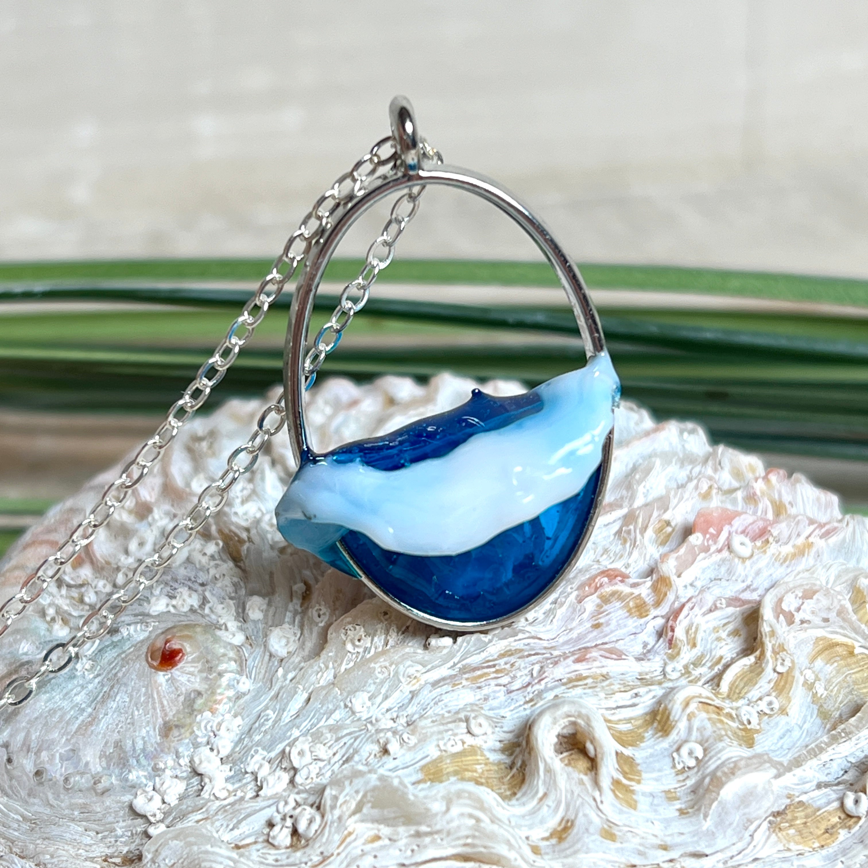 Ovale Halskette „Ocean Crest“ mit 3D-Welle: handgefertigter Harz-Anhänger in Silber-Legierung, Farbverlauf von Tiefblau zu Türkis mit weißer Schaumkrone. Größe ca. 3,9 × 2,3 cm, an einer ca. 56 cm langen versilberten Kette. Glänzende Oberfläche, maritimer Look, Unikat-Handarbeit.