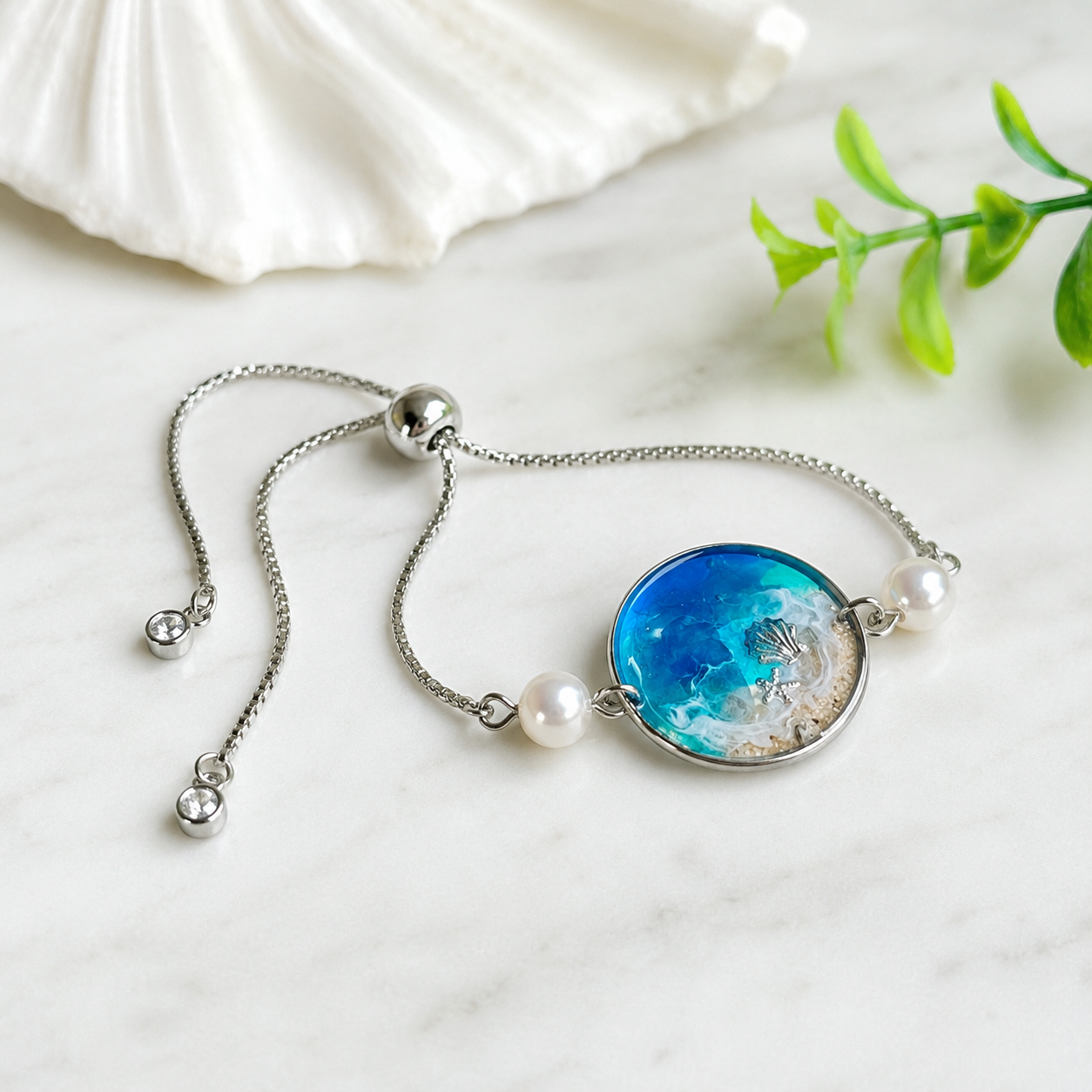 Handgefertigtes Edelstahl Armband MEERESZAUBER mit Süßwasserperlen und rundem Resin Mittelteil im maritimen Design, meerblauer Welle, Sandoptik, Muschel und Seestern, stufenlos verstellbarer Schiebeverschluss, Unikat von ZeitlosSchmuckDesign.