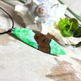 Anhänger aus Nussbaumholz und fluoreszierendem Epoxidharz in Grün-Weiß. Größe ca. 5,8 × 2 cm, Edelstahlöse, Lederkette 45+5 cm. Handgefertigtes Unikat.
