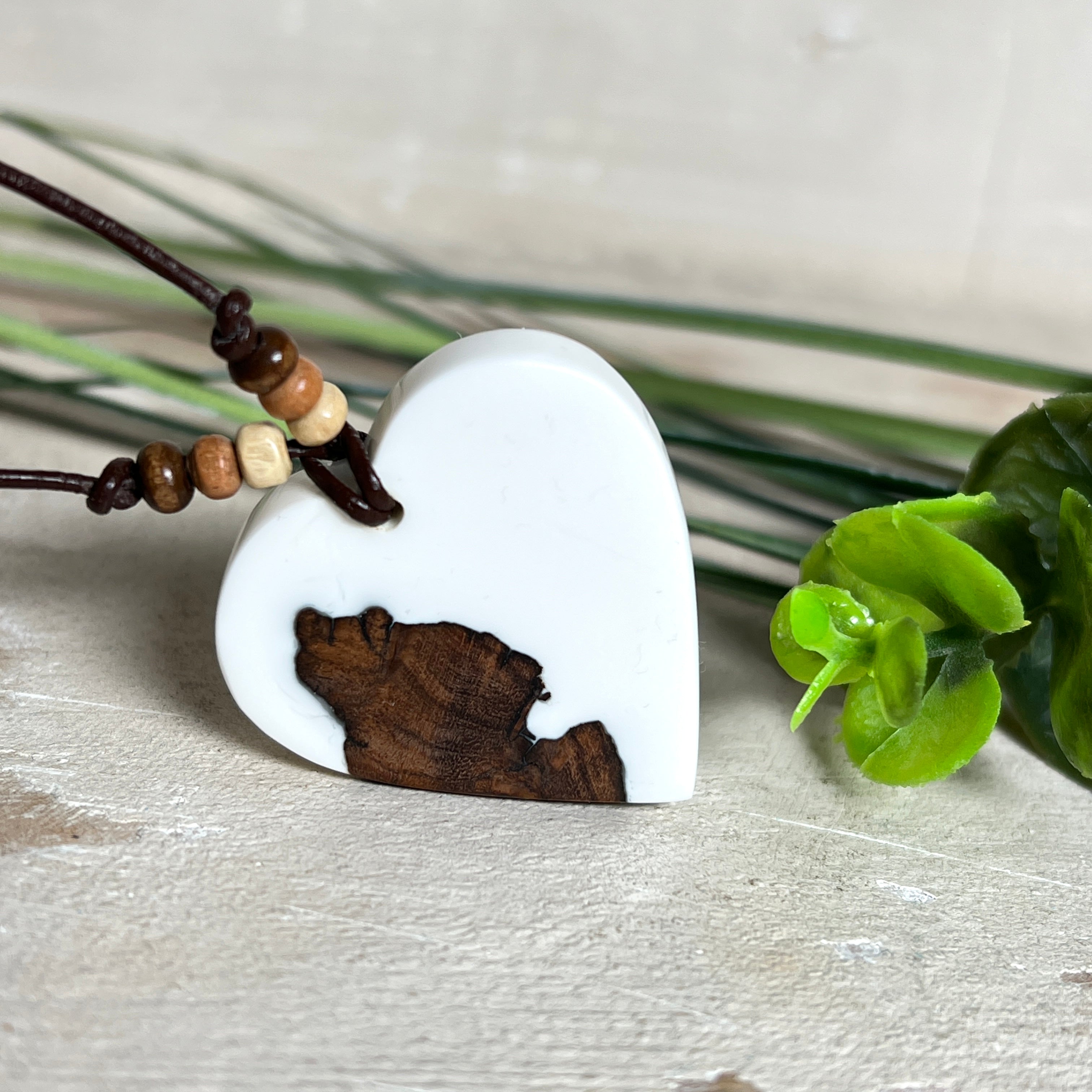 Herzanhänger „Pure Heart“ aus Maserholz und weißem Epoxidharz. Handgefertigtes Unikat mit kontrastreichem Design – die natürliche Maserung des Holzes trifft auf die klare Reinheit von Weiß. Größe ca. 3,5 × 3,5 cm. Verstellbares Lederband (23–41 cm) mit Holzperlen. Ein edles Schmuckstück, inspiriert von Natur und Liebe.