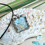 Quadratischer Larimar-Mosaik Anhänger im Edelstahlrahmen mit Seestern-Element und facettierter Bergkristall-Perle, eingebettet in Harz, an schwarzer Lederkette.