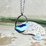 Ovale Halskette „Ocean Crest“ mit 3D-Welle: handgefertigter Harz-Anhänger in Silber-Legierung, Farbverlauf von Tiefblau zu Türkis mit weißer Schaumkrone. Größe ca. 3,9 × 2,3 cm, an einer ca. 56 cm langen versilberten Kette. Glänzende Oberfläche, maritimer Look, Unikat-Handarbeit.