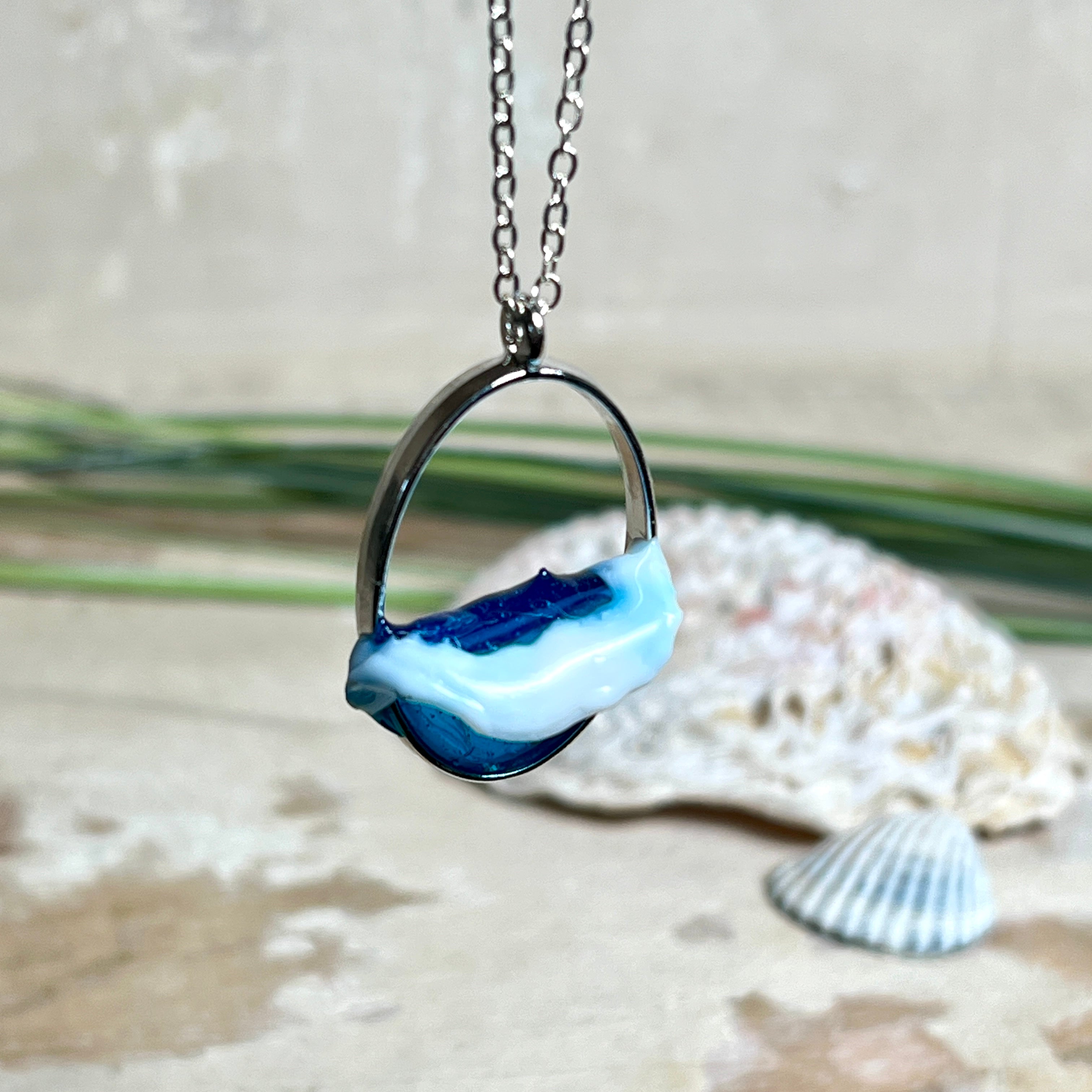 Ovale Halskette „Ocean Crest“ mit 3D-Welle: handgefertigter Harz-Anhänger in Silber-Legierung, Farbverlauf von Tiefblau zu Türkis mit weißer Schaumkrone. Größe ca. 3,9 × 2,3 cm, an einer ca. 56 cm langen versilberten Kette. Glänzende Oberfläche, maritimer Look, Unikat-Handarbeit.