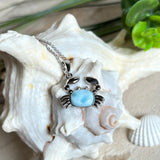 Krabben-Anhänger „Crab of Light“ aus rhodiniertem 925 Sterling Silber mit seltenem Larimar Edelstein aus der Dominikanischen Republik. Der Anhänger (28 × 18 mm) wird mit einer feinen 45 cm langen Silberkette geliefert. Symbol für Schutz, Intuition und die Kraft des Meeres – jedes Schmuckstück ein Unikat durch das natürliche Farbspiel des Larimars.