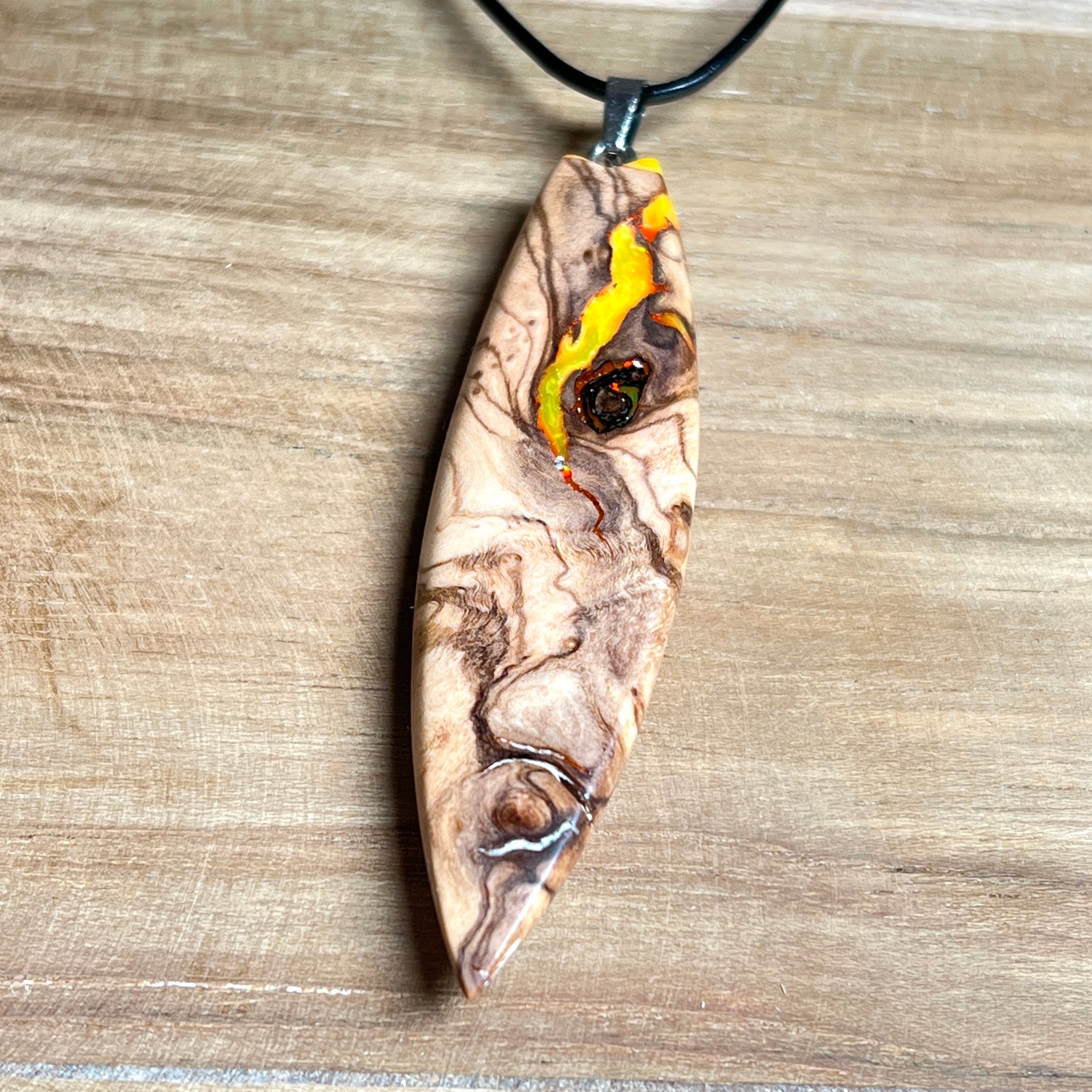 Handgefertigter Surfbrett-Anhänger aus Olivenholz und fluoreszierendem Harz in Gelb und Orange. Das leuchtende Harz beginnt unter Schwarzlicht intensiv zu strahlen und macht den Anhänger zu einem echten Highlight. Größe ca. 6,3 × 2 cm, mit Edelstahl-Anhängerschlaufe und Lederkette mit Edelstahlverschluss und 5 cm Verlängerung. Jedes Schmuckstück ist ein Unikat – Maserung und Farbspiel sind einzigartig. Ideal für Naturliebhaber und Individualisten.