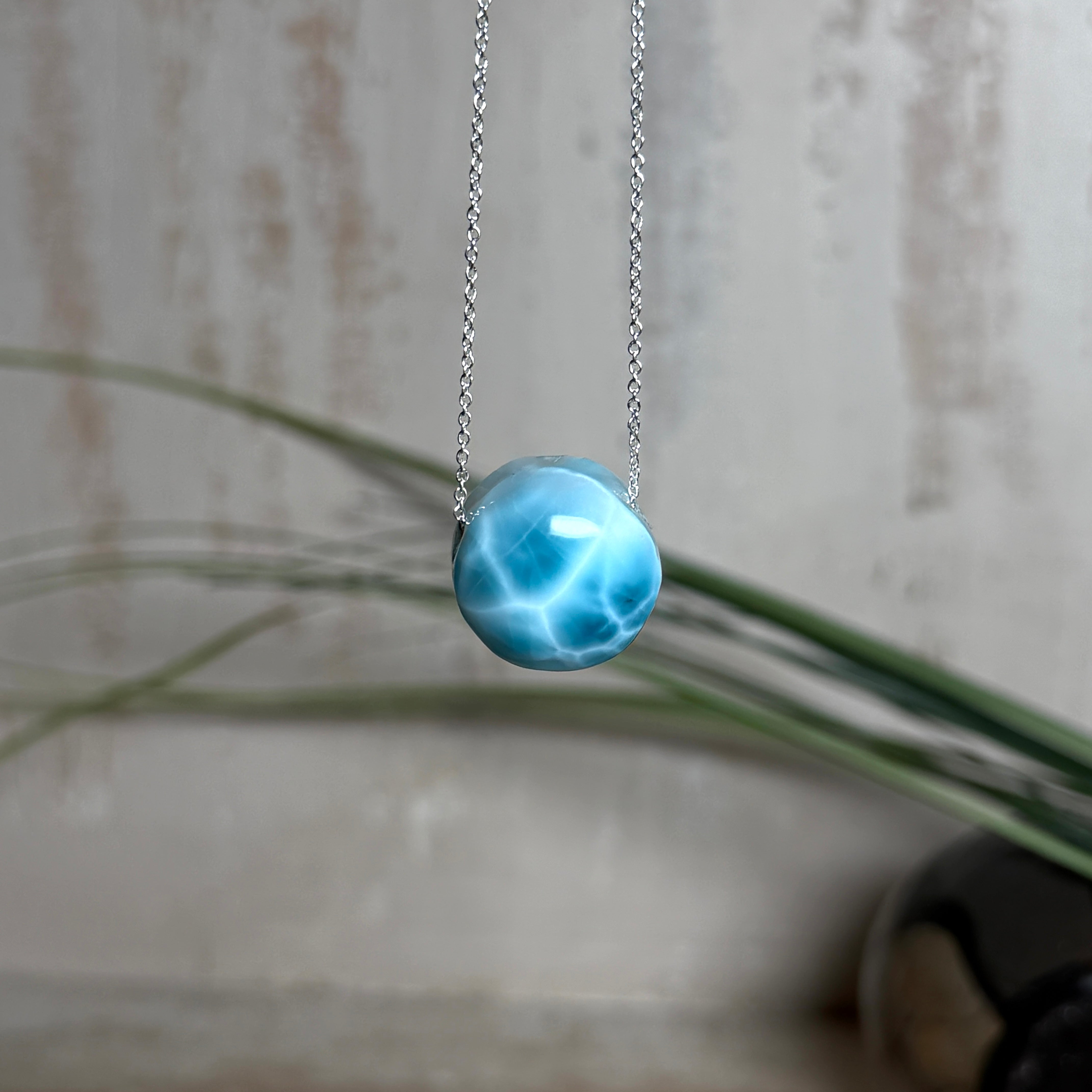 Feine Kette mit rundem Larimar-Cabochon in AA-Qualität. Der ca. 20 mm große Stein zeigt ein intensives Blau mit hellen, netzartigen Zeichnungen und ist mittig mit einer 2,5 mm Bohrung versehen, durch die eine zarte 925 Silberkette (45 cm, ca. 1 mm stark) geführt wird. 