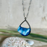 „Lagunenlicht“ – Tropfenanhänger mit handmodellierter 3D-Welle und feinem Glitzereffekt. Klarer Harzlook in Blau/Türkis, gefasst in Silber-Legierung. Größe ca. 3,5 × 2 cm. Geliefert an einer versilberten Kette (ca. 56 cm). Hochglänzend , maritimer Unikatcharakter.