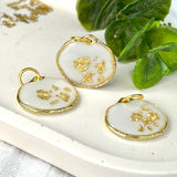 Gold-colored pendant with gold flakes, background in white and fluorescent under black light, birthday, gift
