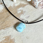 Larimar Freeform Anhänger mit rhodinierter Silberöse an schwarzer Lederkette. Der seltene, kostbare Larimar („Atlantisstein“) zeigt ein lebendiges Muster aus Türkis- und Weißtönen. Beidseitig tragbar, Steingröße ca. 2 x 1 cm, Lederkette 45 cm mit Edelstahl-Karabiner und 5 cm Verlängerung. Natürlicher, maritimer Unikatschmuck.