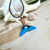 Handgefertigter Walflossen-Anhänger aus Olivenholz und Epoxidharz in Blau-Grün-Weiß, polierte Oberfläche, Edelstahl-Öse. Schwarze Lederkette 45 cm mit Edelstahl-Karabinerverschluss und 5 cm Edelstahl-Verlängerung. Anhängergröße ca. 2,5 × 3,2 cm, maritime Produktfotografie.