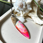 Aurora Flame – fluoreszierender Surfbrett-Anhänger aus Maserholz und leuchtendem Epoxidharz in Rosa, Pink, Orange und Weiß. Der handgefertigte Unikat-Anhänger fluoresziert bei Schwarzlicht in intensiven Farbtönen. Er ist ca. 6,3 x 2 cm groß, wird an einem verstellbaren Lederband (26–45 cm) getragen und ist mit einer silberfarbenen Spacerperle verziert. Ein ausdrucksstarkes Schmuckstück für Menschen mit Persönlichkeit.