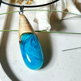 Tropfenförmiger Anhänger aus Maserholz und Harz in leuchtenden Blautönen und Weiß. Inspiriert vom Meer, in Handarbeit gegossen,gesägt, geschliffen und hochglanzpoliert. Mit verstellbarer Lederkette (45 + 5 cm) und Edelstahlkarabiner. Jeder Anhänger ist ein Unikat mit natürlicher Maserung. Ein maritimes Schmuckstück für Naturfreunde und alle, die das Wasser lieben.