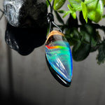 Der handgefertigte Anhänger „Celestial Flame“ kombiniert warmes Olivenholz mit glasklarem Harz und irisierendem Opal. Das einzigartige Farbspiel erinnert an Polarlichter und verleiht dem Schmuckstück eine mystische Tiefe. Die Oberfläche ist glatt poliert, der Anhänger wird an einem verstellbaren Lederband getragen – ein ausdrucksstarkes Unikat für alle, die Naturmaterialien und kreative Farben lieben.