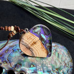 Handgemachter Herzanhänger aus Eibenholz mit lila Harz und Paua-Muschel-Inlay an braunem, verstellbarem Lederband.