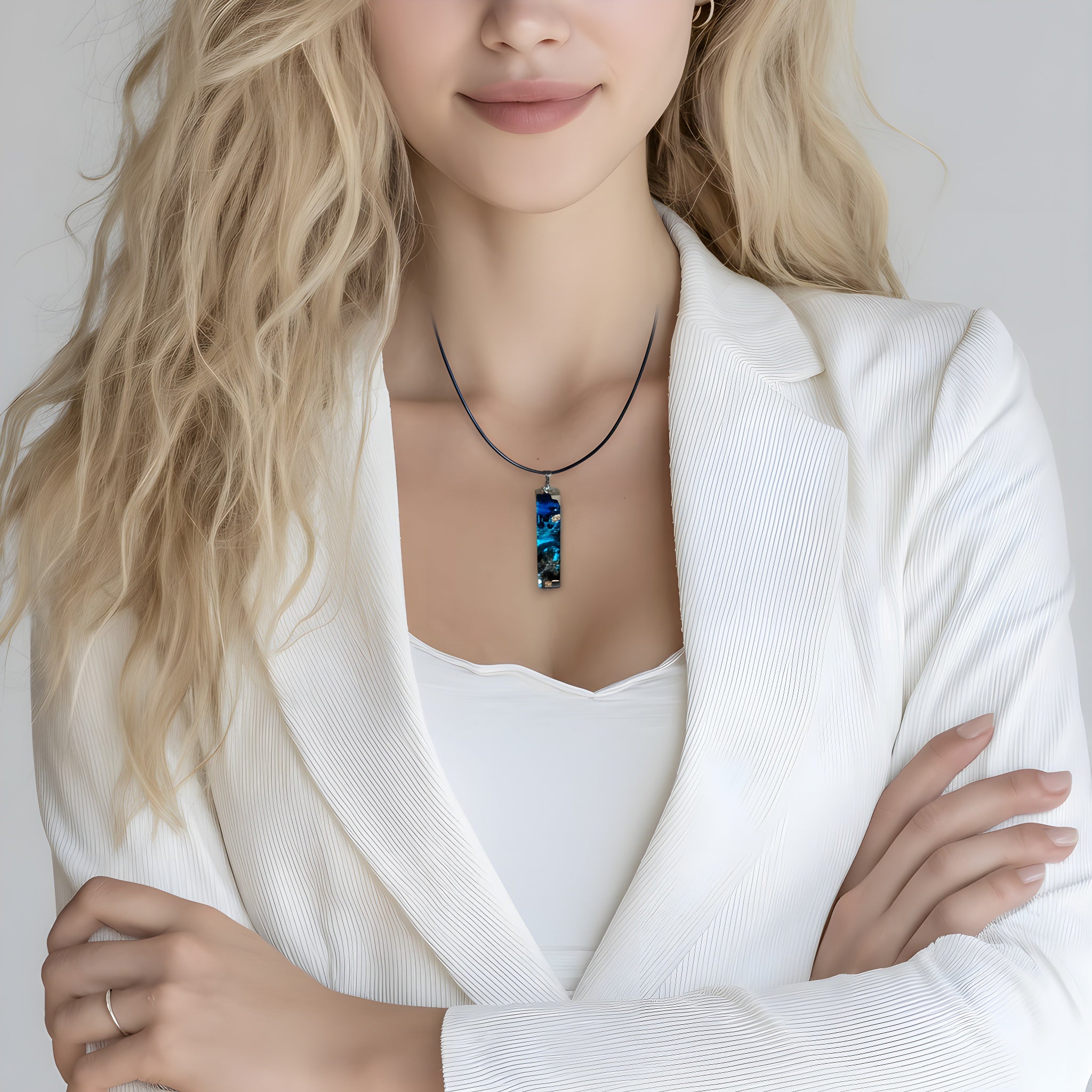 Rechteckiger Stabanhänger aus Maserholz und glasklarem Epoxidharz in tiefen Blau- und Türkistönen mit organischer Lagunen/Riff-Optik. Hochglanzpoliert, ca. 4,6 × 1,2 cm. Der Anhänger hängt an einer schwarzen Lederkette mit Edelstahl-Karabiner und 5-cm-Verlängerung (45 + 5 cm); die Anhängerschlaufe ist ebenfalls aus Edelstahl. Handgefertigtes Unikat, Lieferung in edler Schmuckbox – maritimer Look.