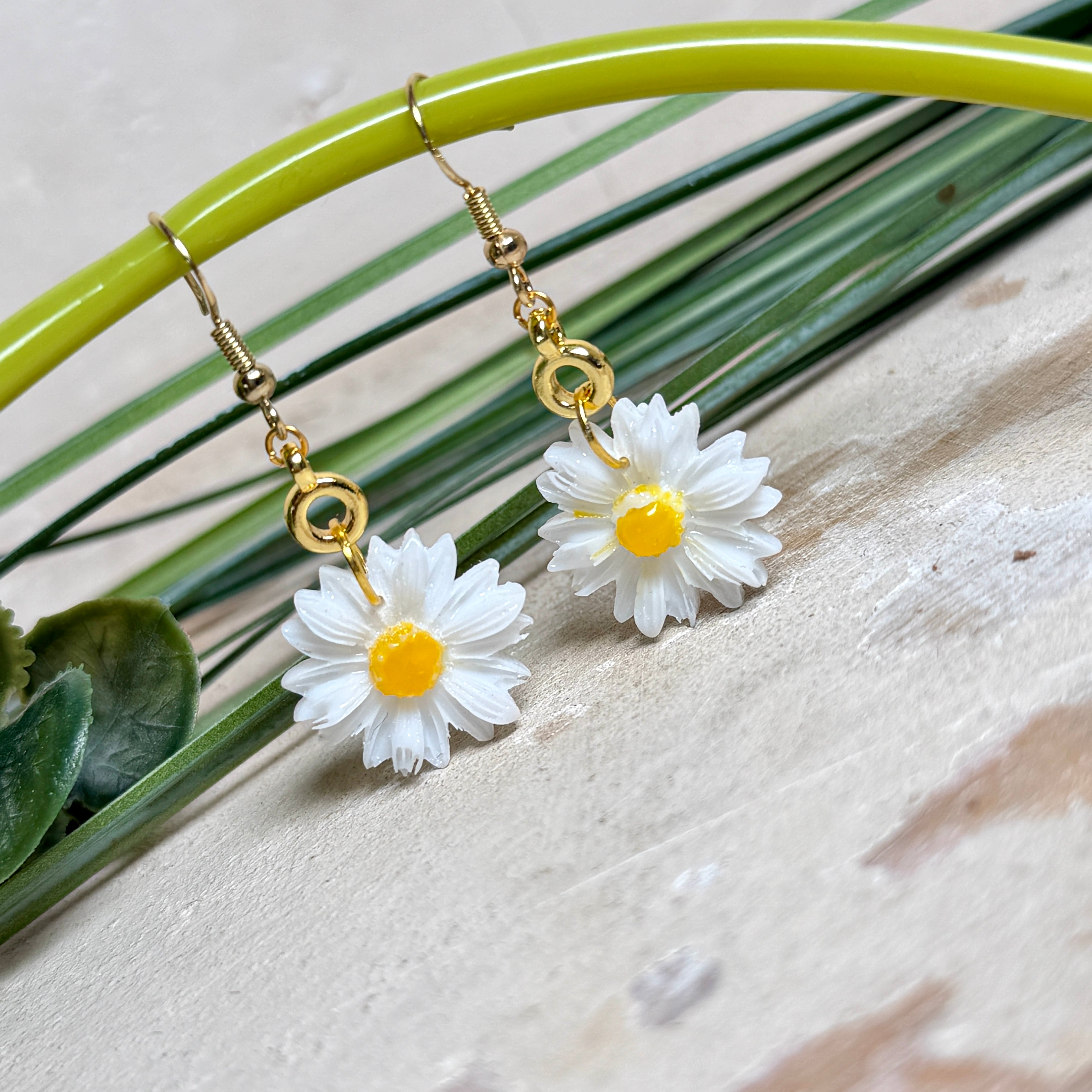 Handgefertigte Gänseblümchen-Ohrringe aus Harz mit 925 vergoldeten Ohrhaken, weiße Blüte mit gelbem Zentrum, goldfarbene Details, Länge ca. 4,5 cm.