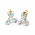 Kleiner Bärchen-Anhänger aus transparentem Harz mit irisierenden Flakes in Regenbogen-Schimmer, goldfarbene Anhängerschlaufe aus Edelstahl. Größe ca. 2,2 × 2,1 cm. Handgefertigtes Unikat; Flakes-Anordnung variiert, vereinzelt kleine Luftbläschen möglich.