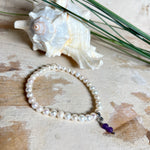 Handgefertigtes Armband „Sea Harmony“ mit schimmernden Süßwasserperlen (Ø ca. 6–7 mm), jede Perle ein Unikat. Auf elastischem Band gefädelt, mit einem filigranen Charmanhänger aus  Amethyst-Perlen, befestigt an einem robusten Edelstahl-Karabiner. Ein Schmuckstück voller Eleganz, maritimer Harmonie und symbolischer Tiefe – ideal als Geschenk oder als stilvolles Accessoire.
