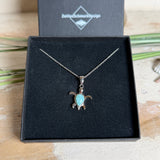 Feine Schildkröten-Kette aus rhodiniertem 925 Silber. Im Panzer des Anhängers liegt ein tropfenförmiger Larimar in hellem Blau. Der Anhänger ist ca. 22 x 18 mm groß und hängt an einer 45 cm langen, 1 mm starken Silberkette.