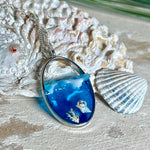 „Riffschatz“ – ovaler Harz-Anhänger mit plastischer 3D-Welle in Blau/Türkis, weißer Schaumkrone und Muschel-/Korallen-Stickern am Grund. Die Sticker sind unter klarem Harz versiegelt. Silber-Legierung, ca. 3,9 × 2,3 cm, an einer ca. 56 cm langen versilberten Kette. Handgefertigt, hochglänzend, jedes Stück ein Unikat.