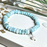 Handgefertigtes Armband aus seltenem Larimar mit facettierten, türkis-blauen Edelsteinperlen (Ø ca. 6–7 mm), elastischem Band und einem zarten Süßwasserperlen-Charm an Edelstahlkarabiner. Der wertvolle Larimar, auch „Stein des Atlantis“ genannt, gilt als Edelstein der Ruhe und Meeresverbundenheit.
