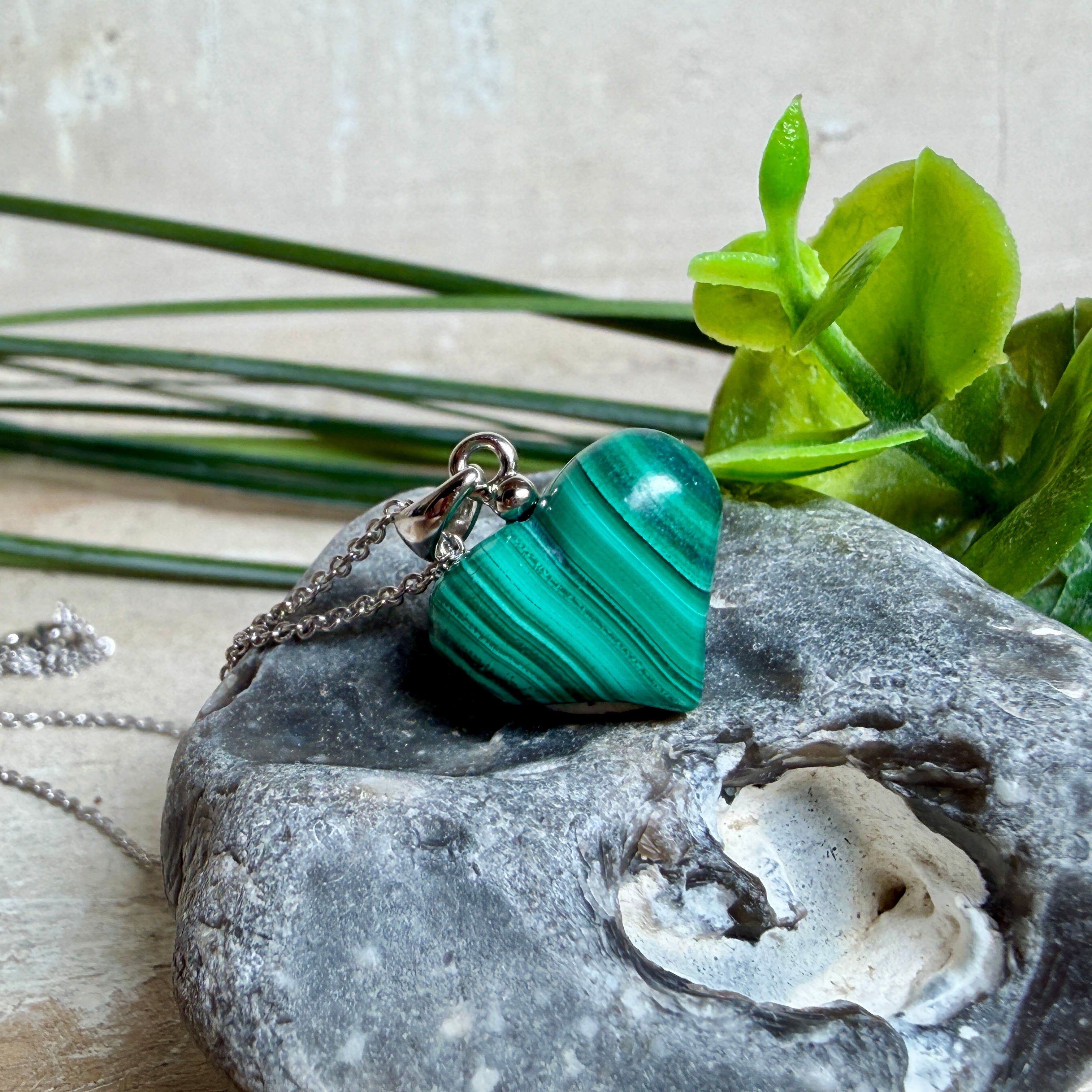 Halskette mit Malachit-Herz: kleiner, gewölbter Herzanhänger aus intensiv grün gebändertem Malachit, ca. 16 x 14 x 10 mm, in hochglanzpolierter, rhodinierter 925 Silberfassung an feiner Ankerkette aus Silber.