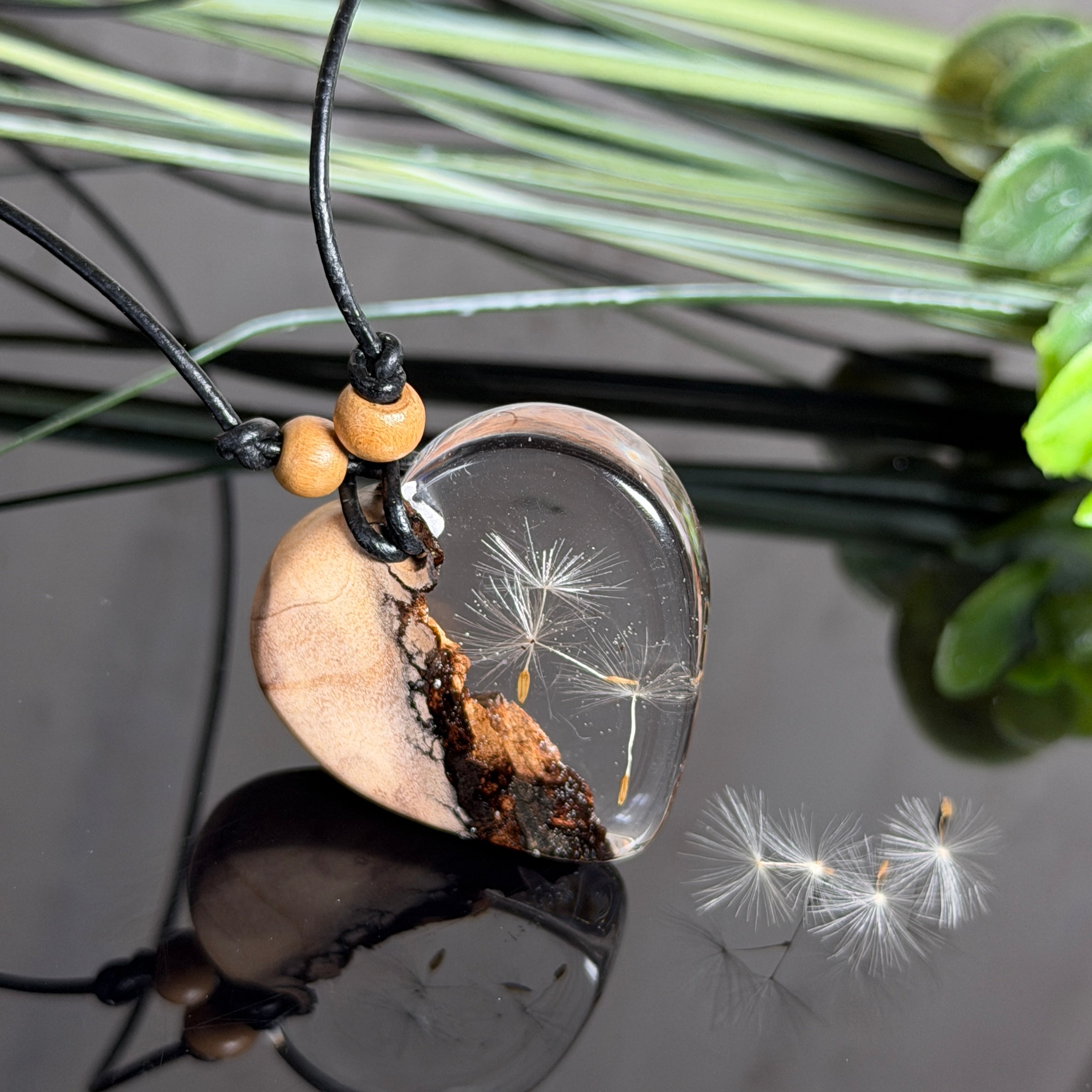Handgefertigter herzförmiger Anhänger aus Olivenholz und klarem Epoxidharz mit echten schwebenden Pusteblumensamen, an verstellbarer schwarzer Lederkette mit Holzperlen, Unikat 