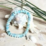 Handgefertigtes Armband aus seltenem Larimar mit facettierten, türkis-blauen Edelsteinperlen (Ø ca. 6–7 mm), elastischem Band und einem zarten Süßwasserperlen-Charm an Edelstahlkarabiner. Der wertvolle Larimar, auch „Stein des Atlantis“ genannt, gilt als Edelstein der Ruhe und Meeresverbundenheit.