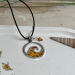 “Runder Wellenanhänger aus Edelstahl mit Bernstein-Harz-Inlay, Jaspisperle & facettiertem Bergkristall an schwarzer Lederkette (45 cm + 5 cm).”