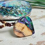 Handgemachter Herzanhänger aus Eibenholz mit lila Harz und Paua-Muschel-Inlay an braunem, verstellbarem Lederband.