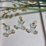 Kleiner Bärchen-Anhänger aus transparentem Harz mit irisierenden Flakes in Regenbogen-Schimmer, goldfarbene Anhängerschlaufe aus Edelstahl. Größe ca. 2,2 × 2,1 cm. Handgefertigtes Unikat; Flakes-Anordnung variiert, vereinzelt kleine Luftbläschen möglich.