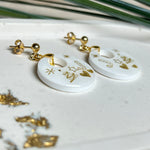 Handgefertigte Ohrringe aus weißem und klarem Harz mit goldenen Weihnachtsmotiven – Sterne, Herzen, Tannenbaum und Zuckerstange. Ohrstecker aus 925 Silber vergoldet, Anhängerschlaufe vergoldet. Größe ca. 37 mm × 25 mm. Leichte, elegante Festtagsohrringe mit warmem Goldglanz und winterlicher Ausstrahlung.