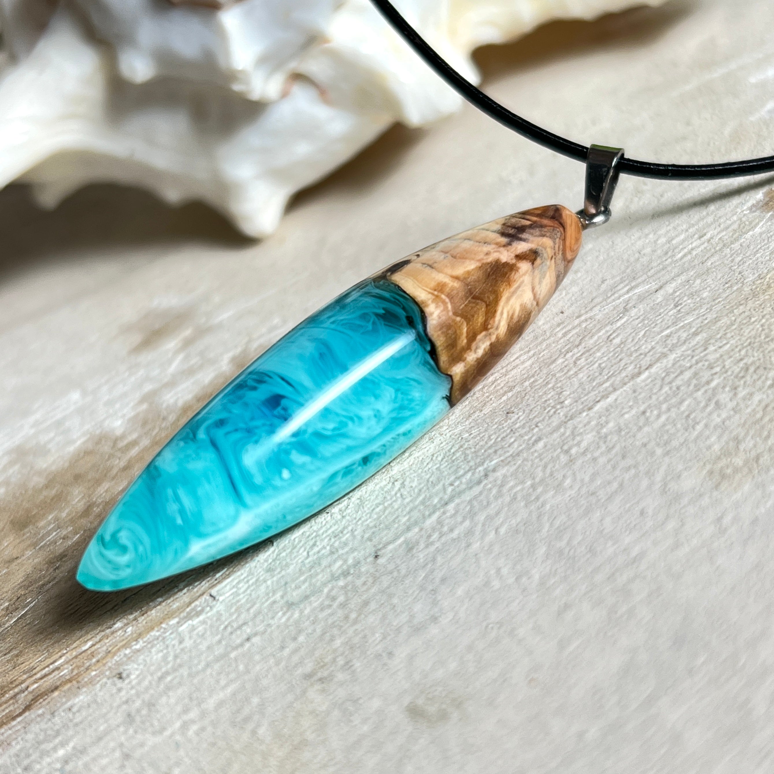 Anhänger aus Eibenholz und Epoxidharz in Blau-Türkis, Weiß und Transparent. Größe ca. 5,8 × 2 cm, Edelstahlöse, Lederkette 45+5 cm. Handgefertigtes Unikat inspiriert vom Ozean.