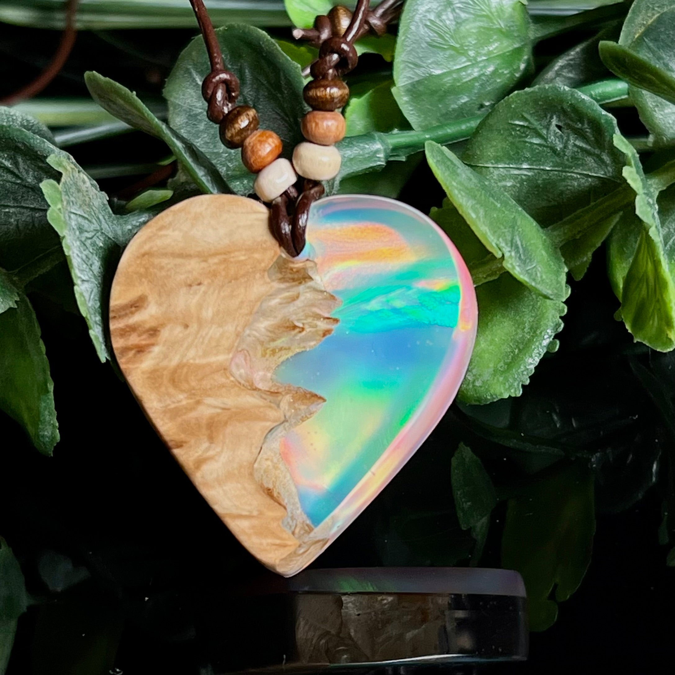 Handgefertigte Herz-Halskette aus naturbelassenem Maserholz und klaren Epoxidharz, in das ein synthetischer Opal eingearbeitet ist. Der Anhänger zeigt ein kunstvolles Zusammenspiel aus warmer Holzmaserung und regenbogenfarbenem Schimmer, der je nach Lichteinfall lebendig leuchtet. Ideal als einzigartiger Holzschmuck, Natur-Schmuckstück oder liebevolle Geschenkidee für besondere Anlässe.