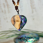 Handgemachter Herzanhänger aus Eibenholz mit lila Harz und Paua-Muschel-Inlay an braunem, verstellbarem Lederband.