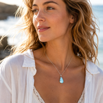 KI-Tragebild MEERESRUHE – Beispiel zur Veranschaulichung der Tragewirkung, zeigt nicht exakt das Original Schmuckstück; filigrane Larimar-Halskette aus 925 Silber mit Tropfen-Anhänger, maritimer Naturstein-Schmuck im eleganten Strandlook.